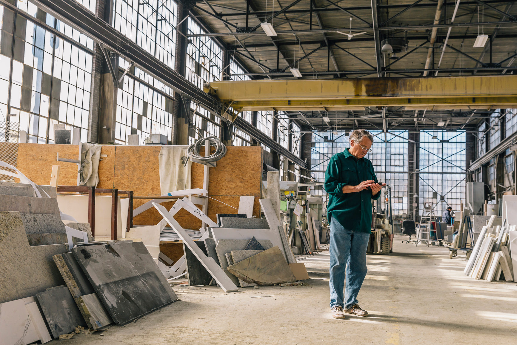 Stock Photo of Senior Man texting on Mobile device at Industrial Workplace